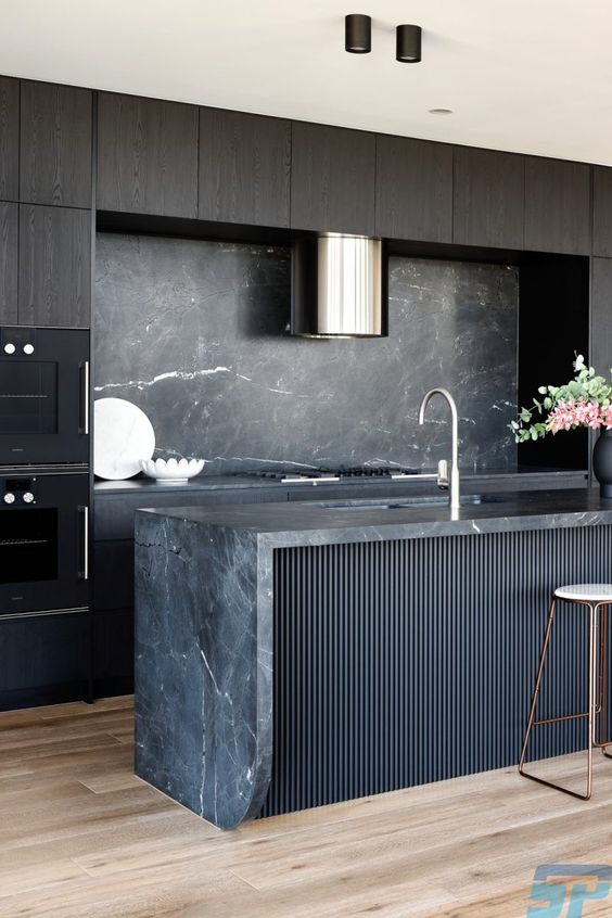an exquisite kitchen with dark-stained cabinets, a black fluted kitchen island, a black marble backsplash and countertops