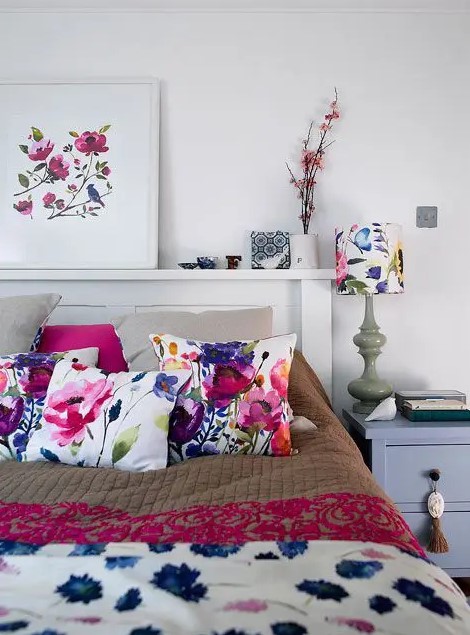 a modern neutral bedroom spruced up with bold floral pillows, a blanket, an artwork and a lamp with a floral lampshade