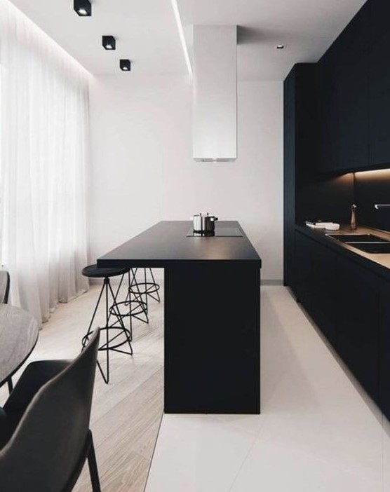 an ultra-minimalist kitchen with sleek black cabinets, built-in lights, a large kitchen island and a white hood