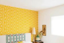 33 a bright bedroom with a yellow printed wallpaper wall, a neutral bed with a statement headboard and a yellow blanket, a pretty artwork is chic