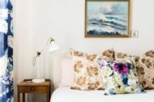 34 a stylish bedroom with printed pillows and bedspreads, bold printed curtains, a nightstand and a white lamp, an ocean artwork