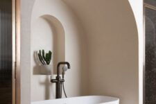 35 a neutral bathroom with an oval tub placed in a niche, with an additional niche with a potted plant looks jaw-dropping