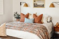 37 a welcoming bedroom in neutrals with a bed with floral and other printed bedding, a stained bench, a chandelier, stained nightstands