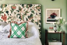 40 a cool and chic bedroom with green walls, a bed with a floral headboard, neutral bedding and a green bedspread, a nightstand and white blooms