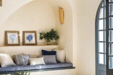 40 an arched niche with a built-in sofa with pillows, a shelf with art and greenery plus a lamp is a cool solution for an entryway