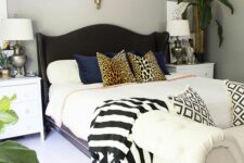 41 a catchy neutral bedroom with a black upholstered bed, mixed print bedding and pillows, potted plants and an upholstered bench