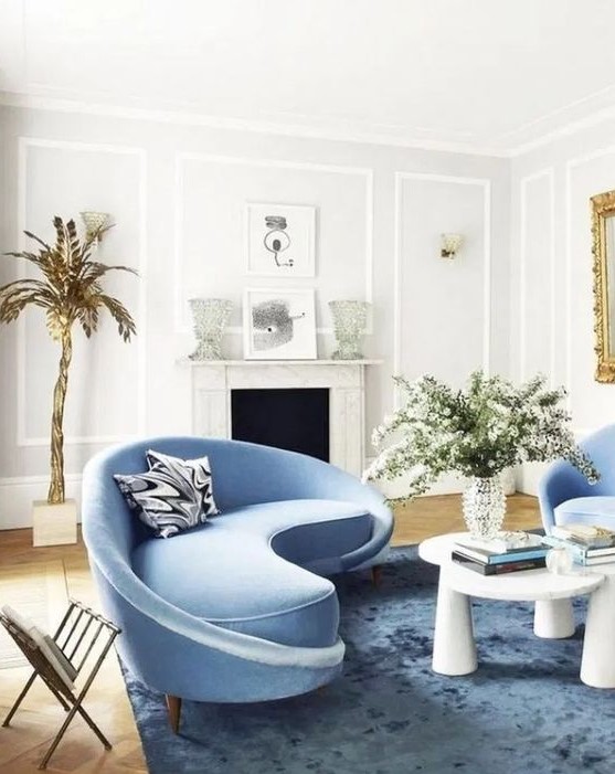 a charming living room with a curved blue sofa and matching chairs and a bold table that catch an eye