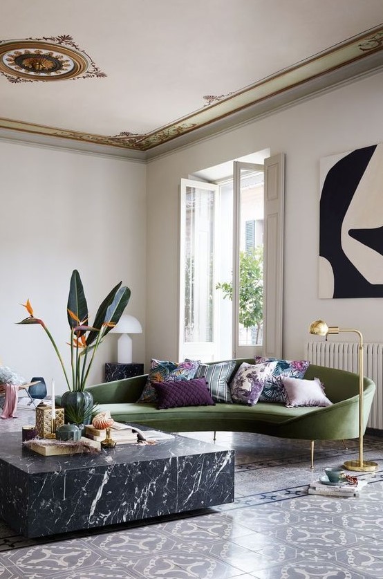 a chic and refined living room done with tiles, a black marble coffee table and a chic green curved sofa as a centerpiece