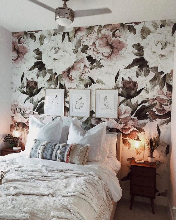 a pretty neutral bedroom with a floral accent wall, a bed with neutral boho bedding, stained nightstands and table lamps