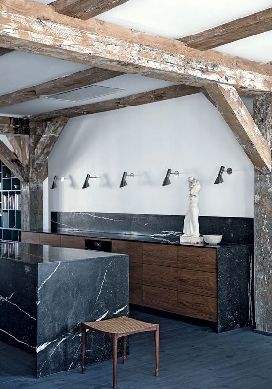 a stylish kitchen with a black marble backsplash and countertops and a matching kitchen island looks cool