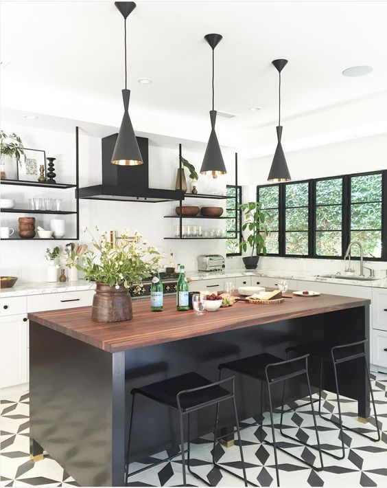 a white farmhouse kitchen accented with a black mosaic floor, a black kitchen island and black pendant lamps