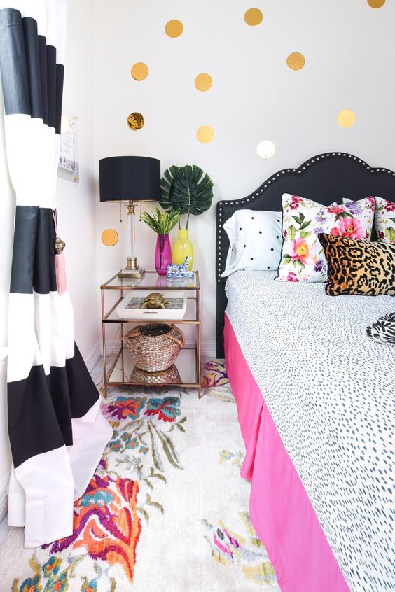 a glam and bold bedroom with a black and pink bed, polka dot, leopard and floral prints, polka dots on the wall and striped curtains