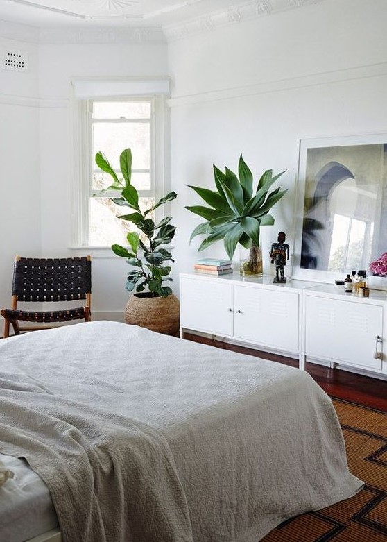 a boho bedroom with two statement plants that catch an eye and refresh the space