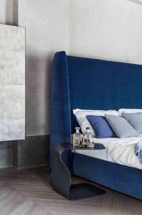 an ultra modern electric blue wingback headboard accented with a catchy curved nightstand