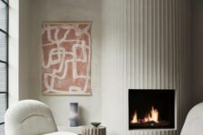 71 a neutral living room with a white fluted fireplace, creamy chairs, a bold printed rug and a bold artwork