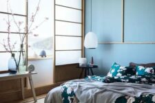 a beautiful blue zen-like bedroom with traditional Japanese sliding doors, a low bed and wooden furniture, blue walls and a ceiling, floral bedding