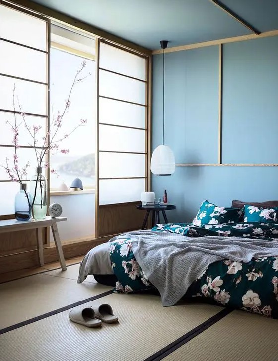 a beautiful blue zen-like bedroom with traditional Japanese sliding doors, a low bed and wooden furniture, blue walls and a ceiling, floral bedding