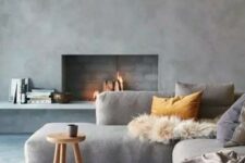 a beautiful minimalist living room with chic furniture, a concrete wall and a fireplace and cozy textiles