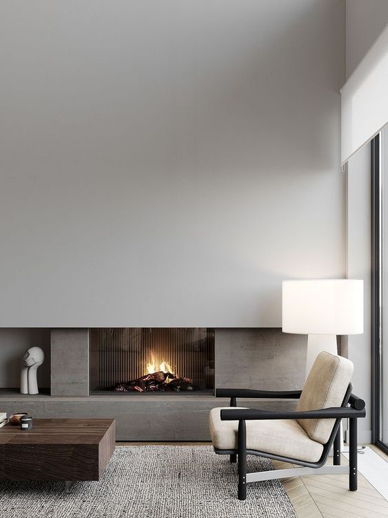 a beautiful neutral living room with a minimalist fireplace surrounded with stone, a dark-stained table and a neutral chair