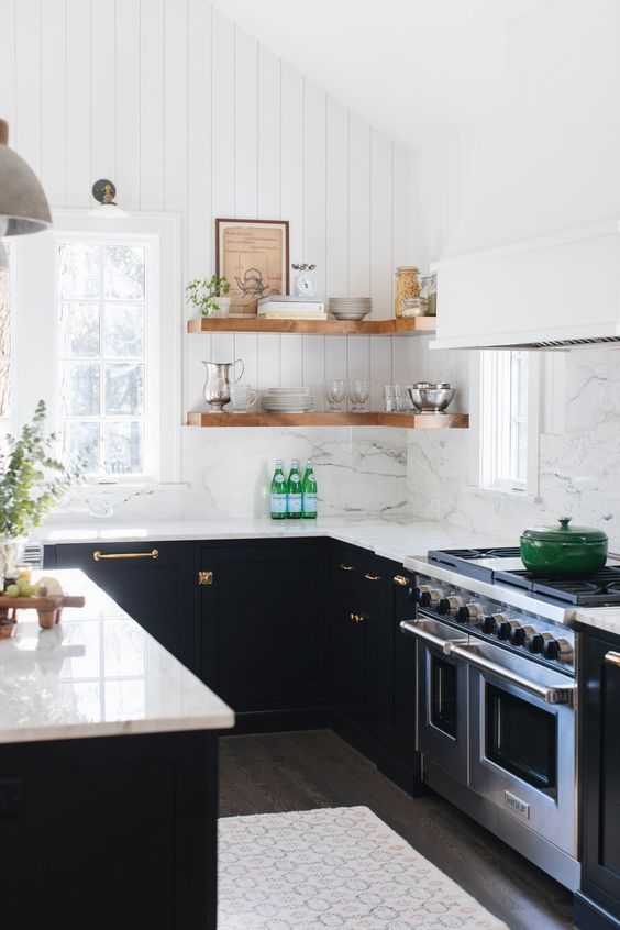 a black U-shaped kitchen with a white marble backsplash and countertops, stained corner shelves and greenery