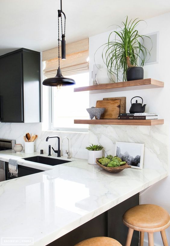 a black and white kitchen with shaker cabinets, a white quartz countertop and a backsplash and open shelves