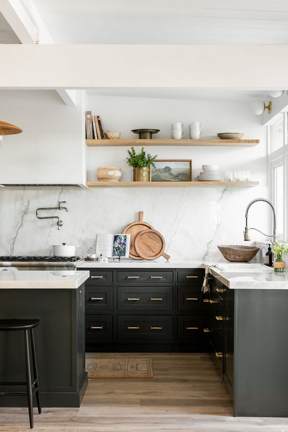 a black farmhouse kitchen with shaker cabinets, a white quartz backsplash and countertops, a white hood and stained shelves