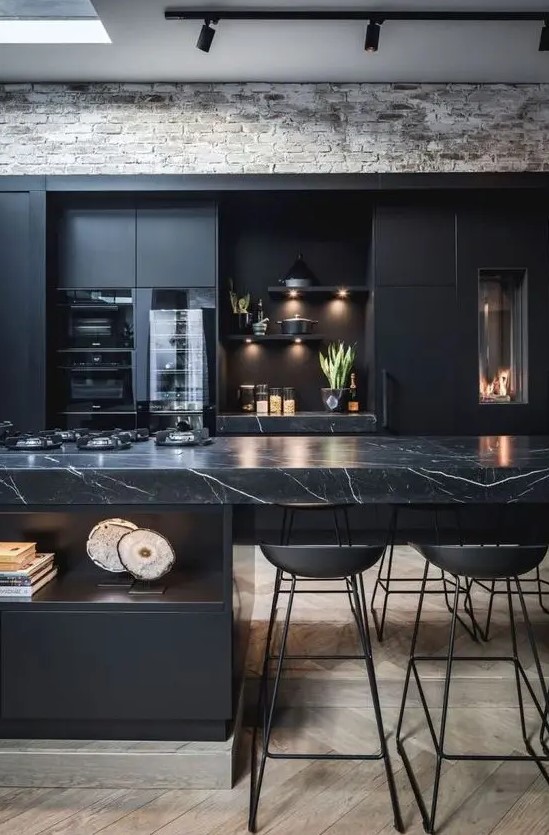 a black moody kitchen with plain cabinets and a stunning black marble kitchen island for a refined feel