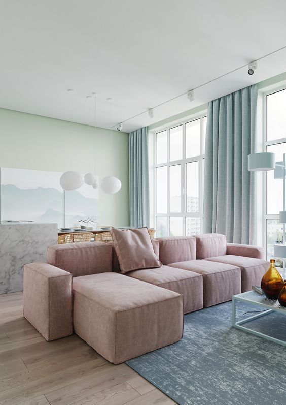  غرف معيشة بألوان الباستيل  A-breezy-pastel-living-room-with-light-green-walls-a-pink-low-sofa-a-blue-coffee-table-blue-curtains-a-marble-slab-table