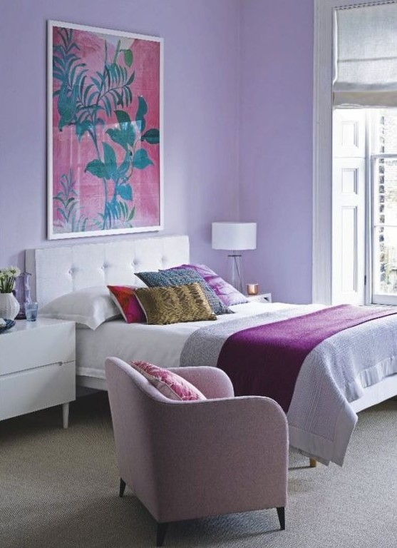 a bright bedroom with lilac walls, a pink chair and bright bedding and pillows is a great place to wake up