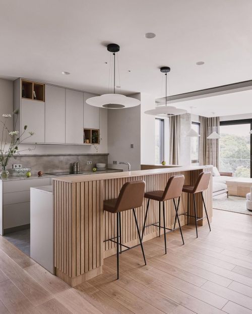 a chic contemporary kitchen with sleek grey cabinets with niches for storage, a double height kitchen island with a fluted part