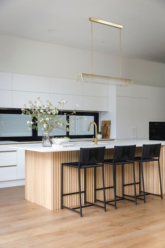 a chic contemporary kitchen with sleek white cabinets, a window backsplash, a ribbed kitchen island with black stools