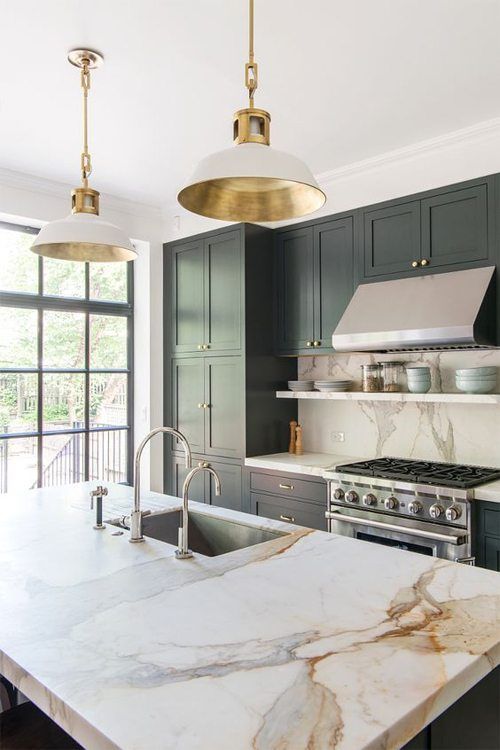 a chic dark green kitchen with shaker cabinets and a matching kitchen island, a white quartz backsplash and countertops