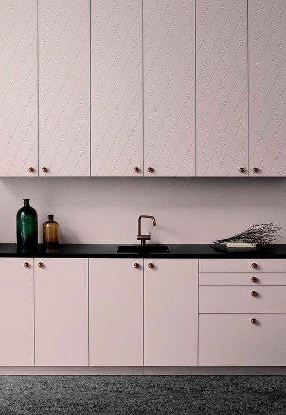 a chic pale pink kitchen with patterned and sleek cabinets, black countertops for a bold contrast