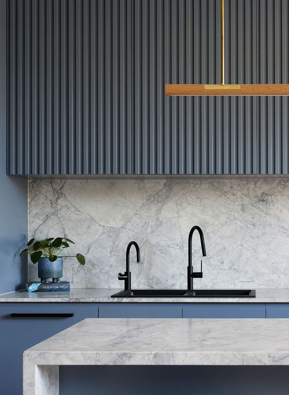 a contemporary kitchen with navy fluted upper cabinets and plain lower ones, a stone backsplash and countertops and black fixtures