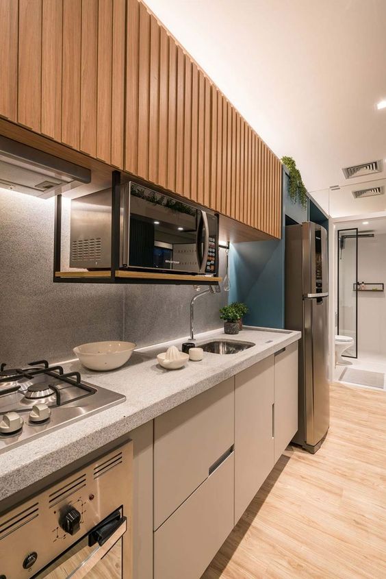 a contemporary kitchen with stained fluted upper cabinets and sleek plain grey lower ones plus a terrazzo countertop and a backsplash