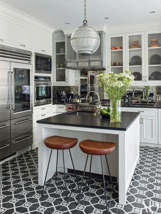a cool black and white farmhouse kitchen with shaker cabinets, black countertops, a black and white tile floor