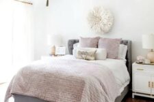 a cool girlish bedroom with a grey bed, pink and neutral bedding, a blush rug, a beaded chandelier and touches of gold