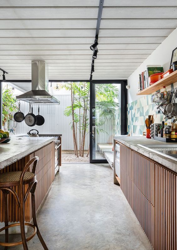a cool indoor outdoor kitchen with ribbed cabinets, concrete countertops, a large matching kitchen island with an eating zone