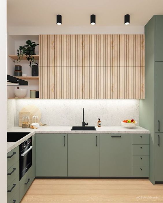 a cool modern kitchen with plain green cabinets and fluted stained upper ones, a white stone countertop and a backsplash, black fixtures