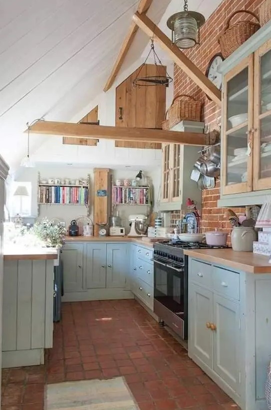 a cottage kitchen with wooden beams, ligth blue shaker cabinets, butcherblock countertops and a tile floor is cozy and cool
