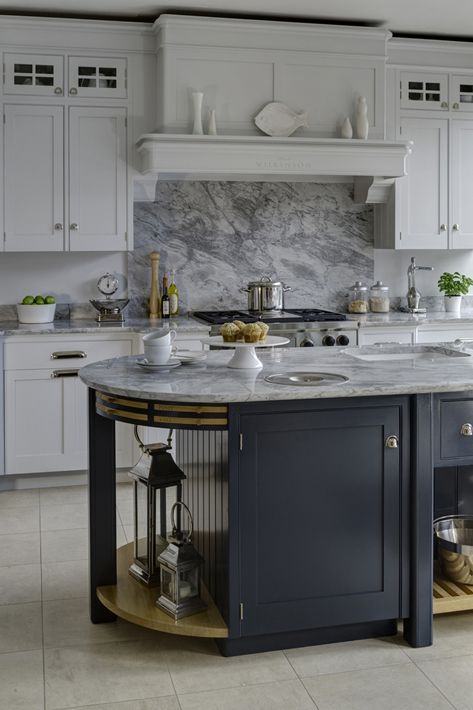 a cozy farmhouse kitchen with shaker style cabinets, a curved kitchen island with a white marbel backsplash and countertops