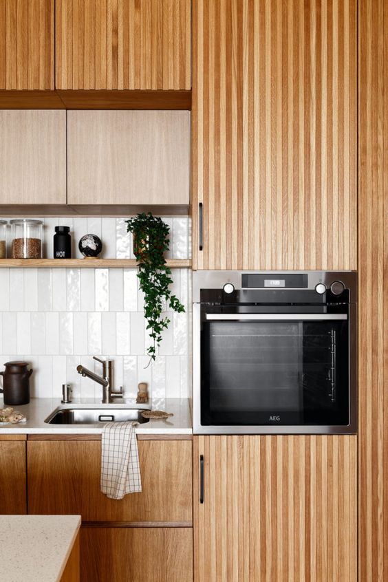 a cozy stained kitchen with plain and ribbed cabinets, a white skinny tile backsplash and an open shelf is a lovely space