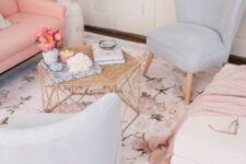 a delicate living room with a pink sofa, pale blue chairs, a pastel floral print rug, a hexagon table with decor