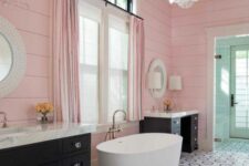 a delightful bathroom with pink slatted walls, black vanities, an oval tub, a geo tiled floor and a scale chandelier