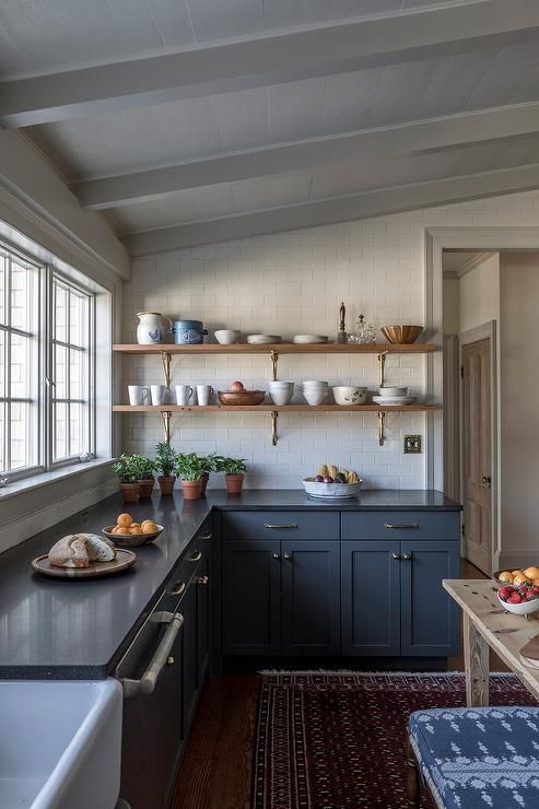 a farmhouse charcoal kitchen with shaker cabinets, black countertops and open shelving for displaying dishes