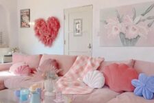 a fun girlish living room with a blush corner sofa, a glass tiered table, a pink grass heart and lots of pastel pillows