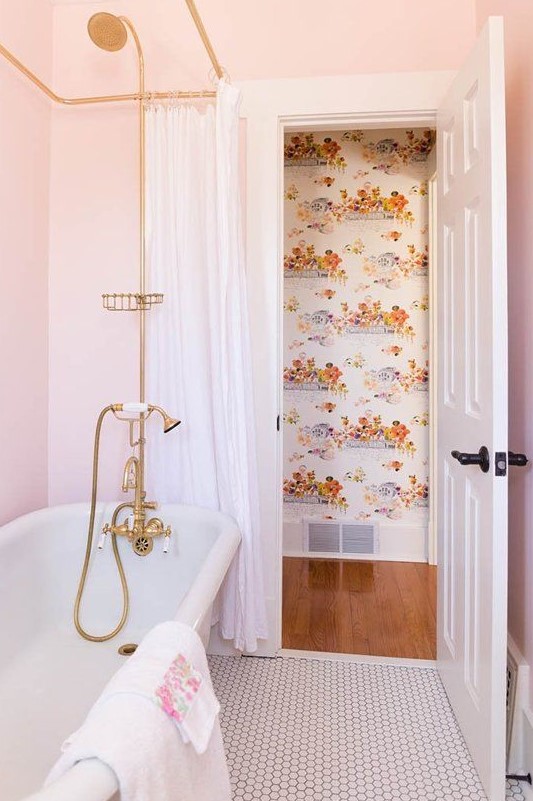 a glam bathroom with light pink walls, gold fixtures and cute floral towels with pink touches