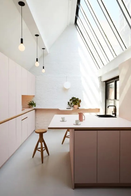 a gorgeous attic kitchen with matte blush plywood cabinets and a large kitchen island accented with black touches and fixtures