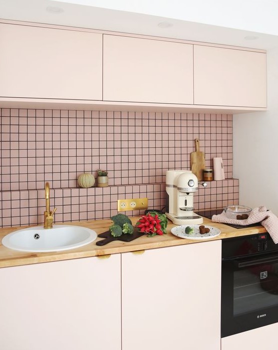a gorgeous blush kitchen with sleek cabinets, gold petal handles, butcherblock countertops and touches of gold