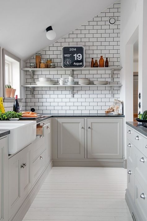 a grey Scandinavian kitchen with shaker cabinets, a white subway tile backsplash and black countertops plus open shelves